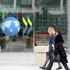 Two women walking in front of a building with the OECD logo. 