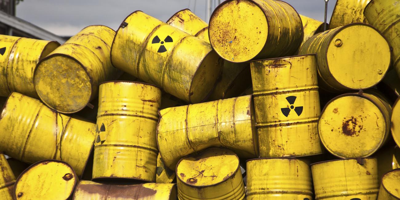 Large yellow chemical drums stacked in an unorganized fashion.
