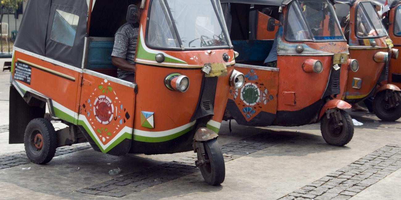 a row of small red rickshaws parked on a street.