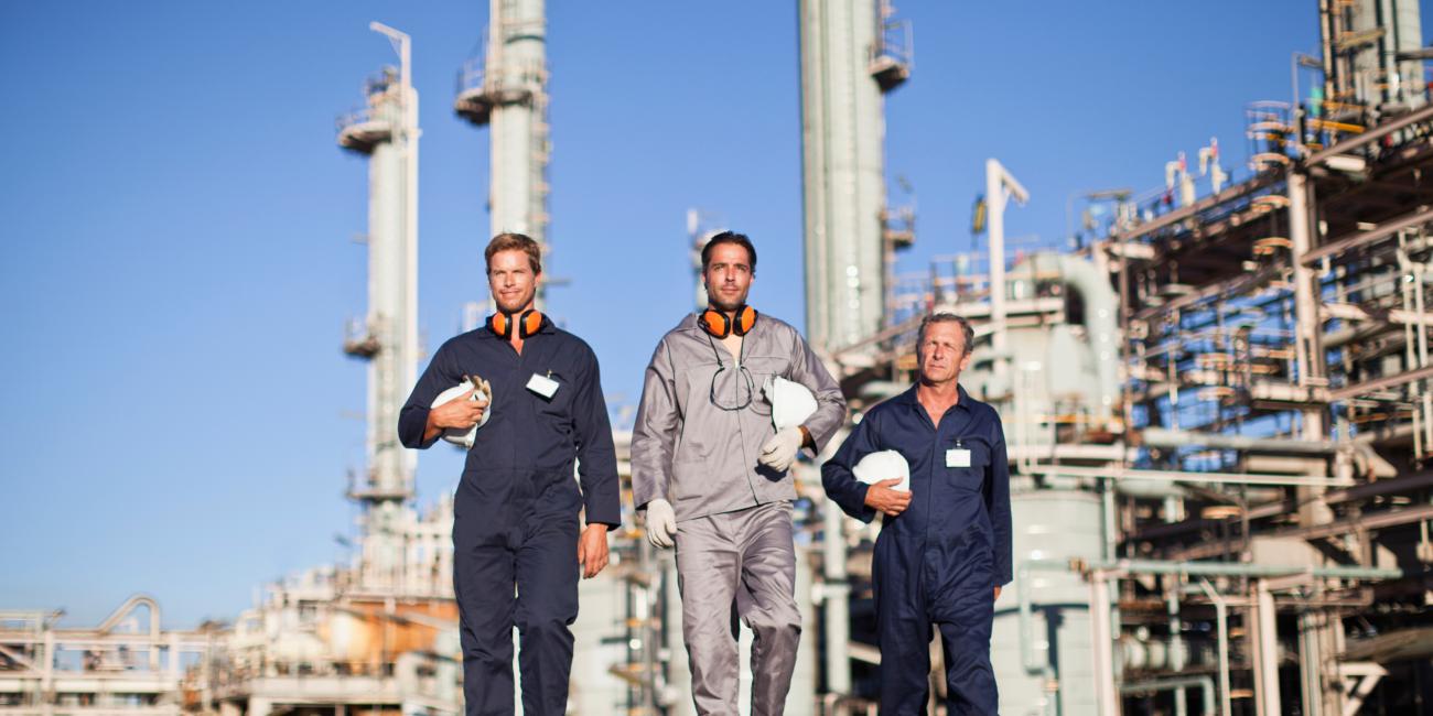 Image of three oil workers walking away from refinery