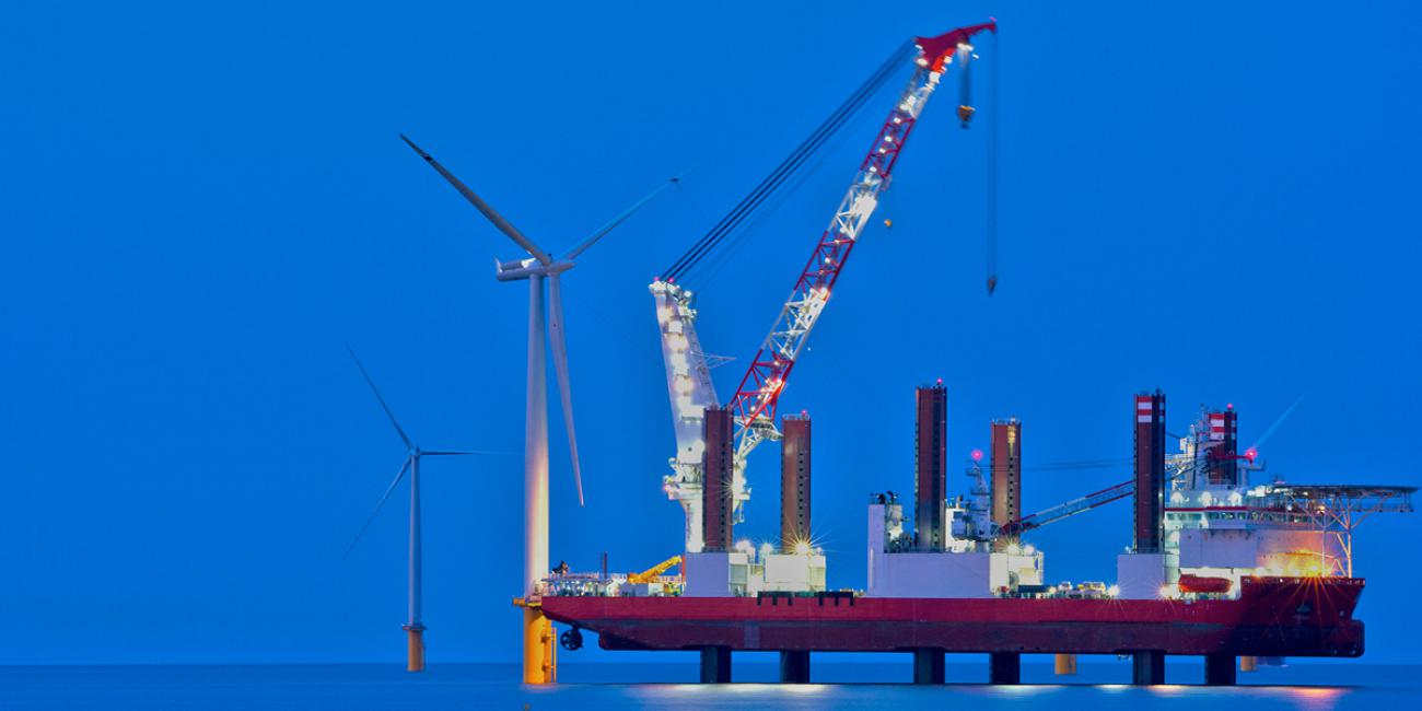 Offshore wind turbines appear behind a construction platform. 