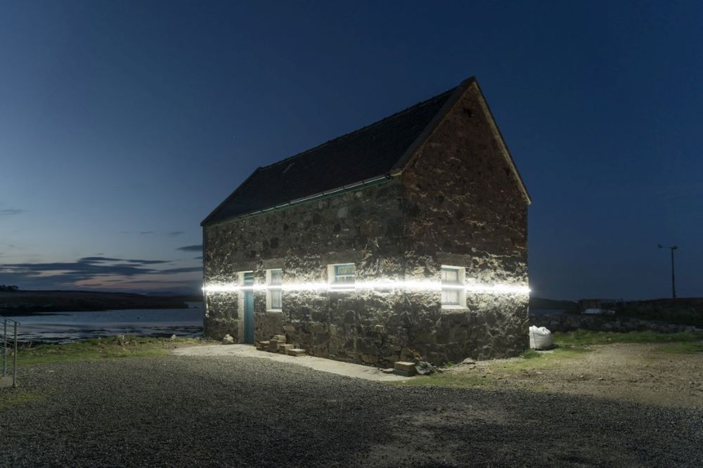 Climate art: Photo of a beam of light on a stone house at night in Scotland
