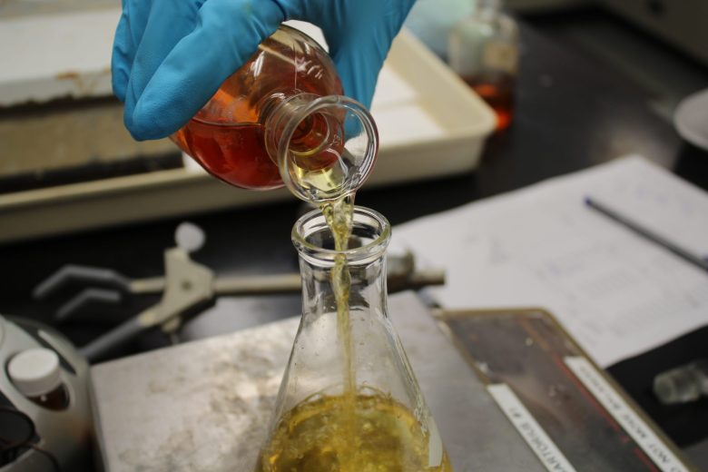 A scientist pours acid into a beaker.