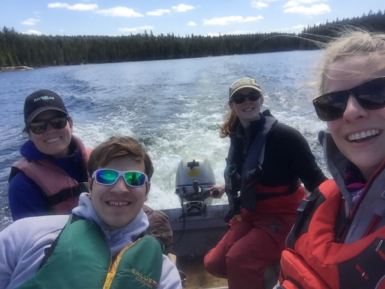 4 scientists in a boat powering towards shore at IISD Experimental Lakes Area in Ontario