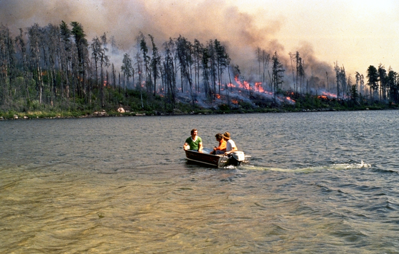 forest fires in the background as researchers are out on a boat on the lake in northern ontario