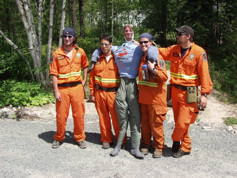 Four researchers wearing orange hold up an effigy of a man.