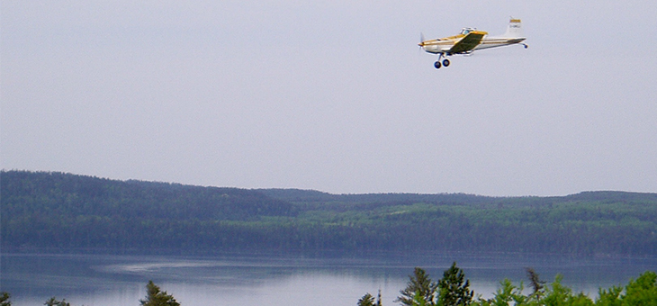 Crop duster flying over freshwater lake spraying into it