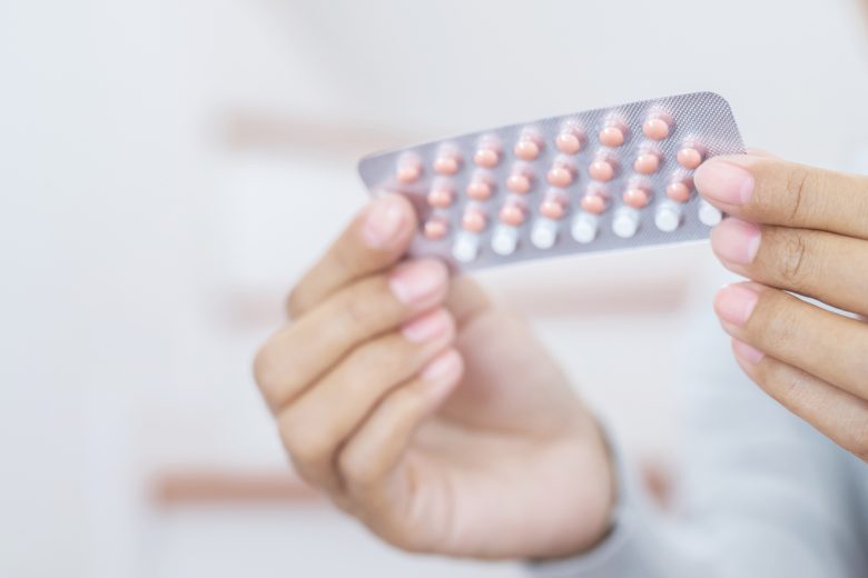 a woman holds a package of birth control pills