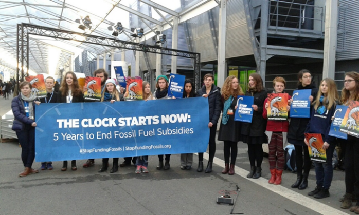 People holding a banner, "The Clock Starts Now: 5 Years to End Fossil Fuel Subsidies"