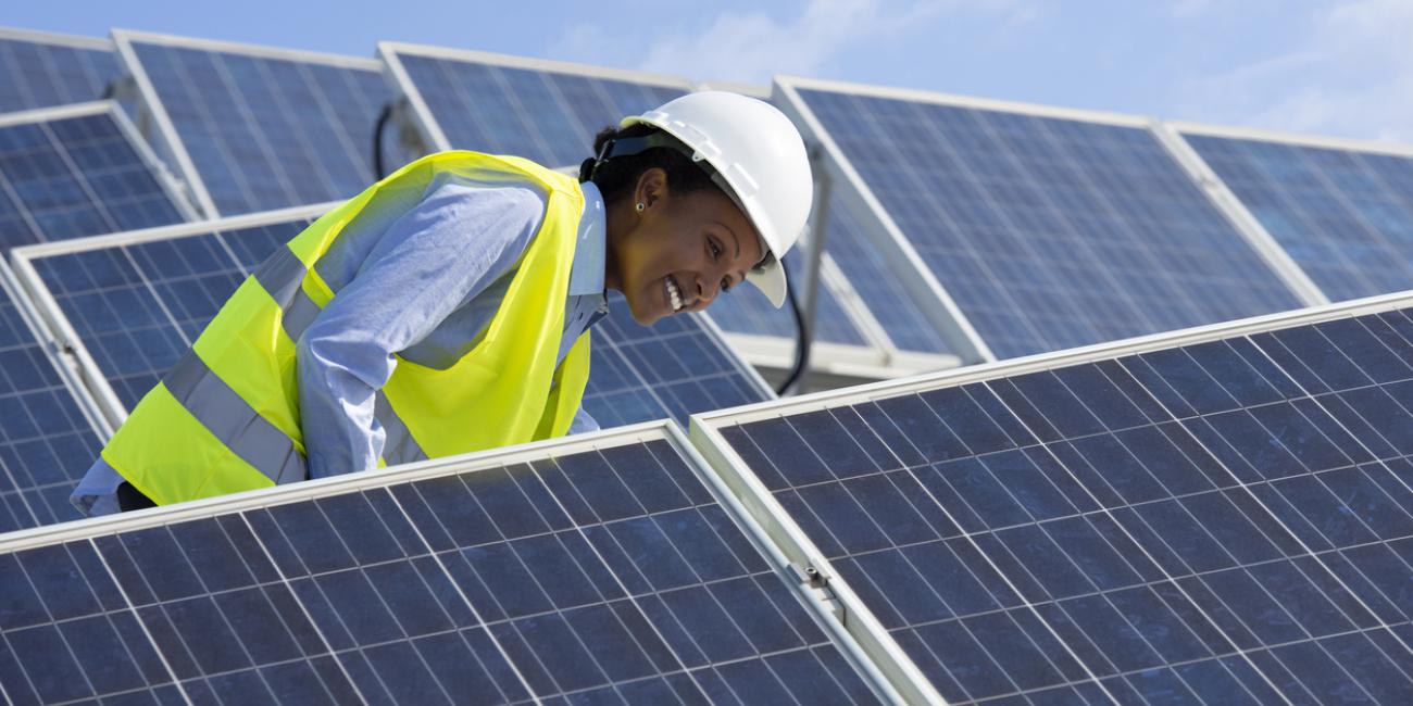 Person in construction vest inspecting solar panels
