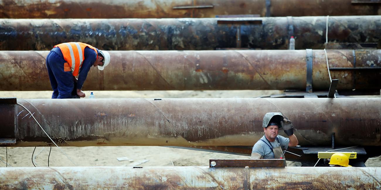 Workers at a construction site in Bucharest, Romania check large pipes.