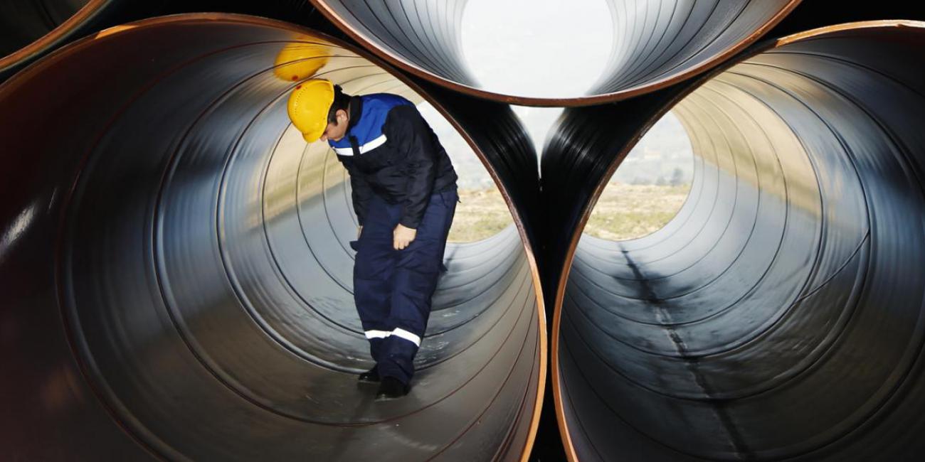 Worker stands in large pipe.