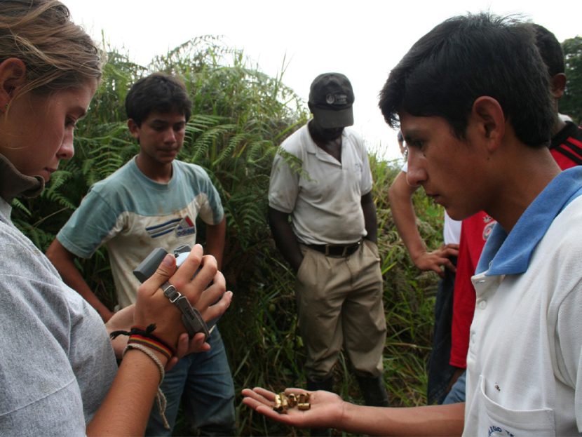 A woman films a young man holding bullet casings.