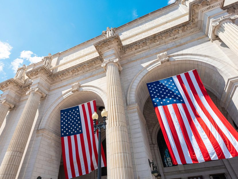 Two American flags hang from a building.