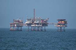 An oil rig platform stands above the sea.
