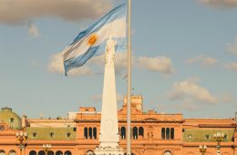 A flag flies next to a statue in front of a building.