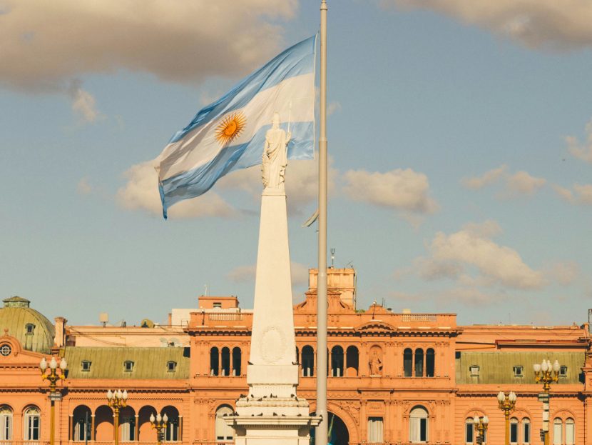 A flag flies next to a statue in front of a building.