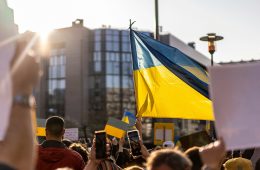 A Ukrainian flag flies above a crowd.