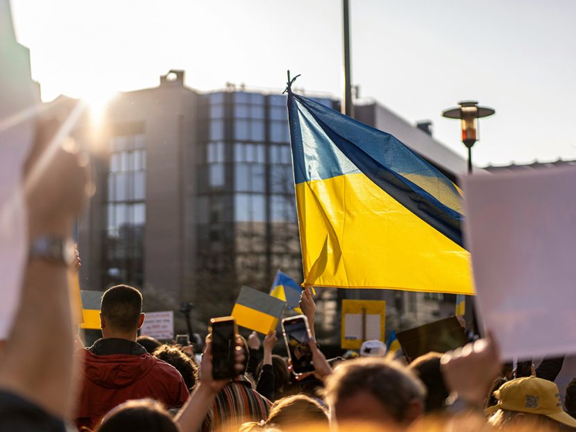 A Ukrainian flag flies above a crowd.