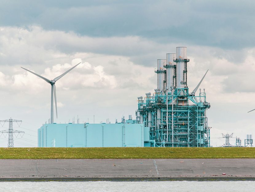 Wind turbines next to an industrial plant.