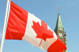 The red-and-white Canada flag flies in front of a government building.