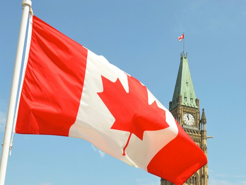 The red-and-white Canada flag flies in front of a government building.