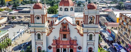 A brown-and-white cathedral in a city.
