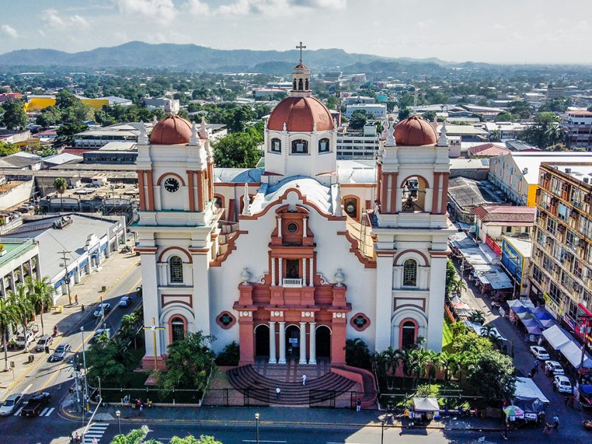 A brown-and-white cathedral in a city.