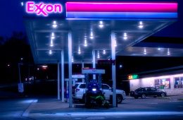 Cars are parked at an Exxon gas station at night.