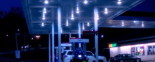 Cars are parked at an Exxon gas station at night.