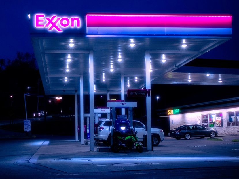 Cars are parked at an Exxon gas station at night.
