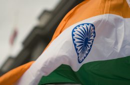 An orange-white-and-green flag with a blue emblem.