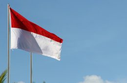A red-and-white flag flies against a blue sky.