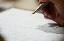 A hand holds a pen over paper.