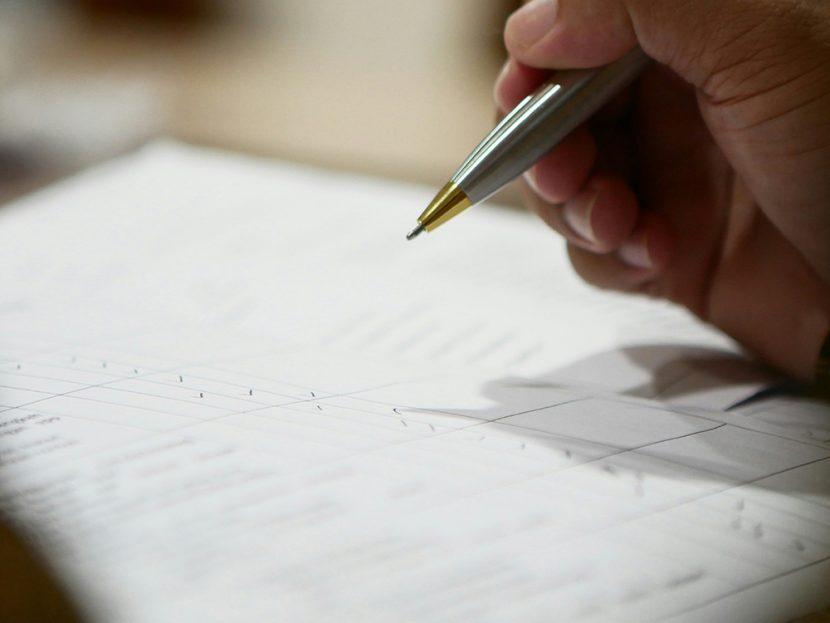 A hand holds a pen over paper.