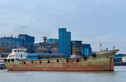A rusted ship is docked at a port.