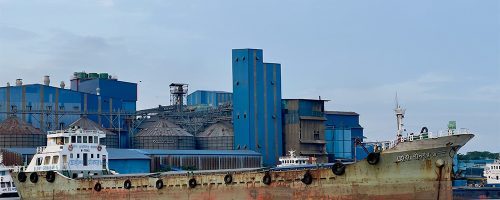 A rusted ship is docked at a port.