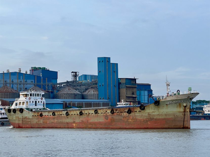 A rusted ship is docked at a port.