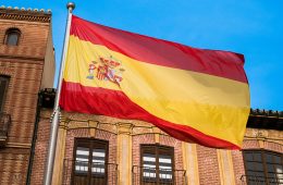 A red-and-yellow flag flies in front of a brown building.