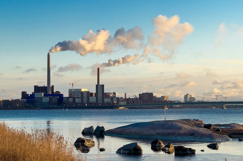 Stacks emit exhaust in an industrial area on a waterfront.