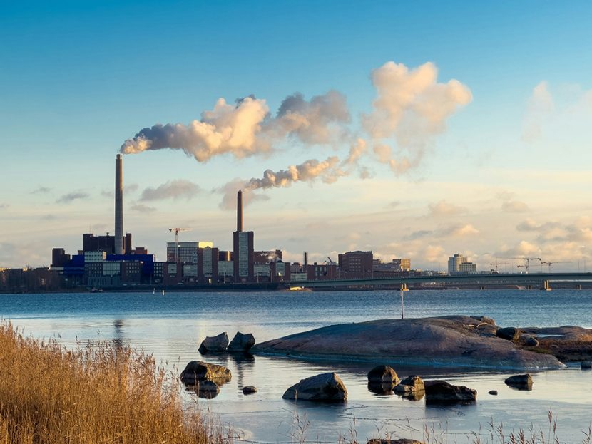 Stacks emit exhaust in an industrial area on a waterfront.