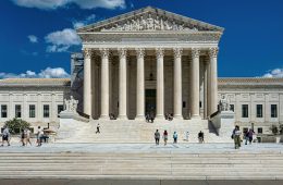 People pass by a grand white building.
