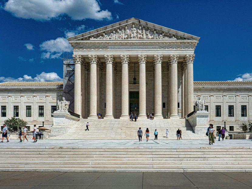 People pass by a grand white building.
