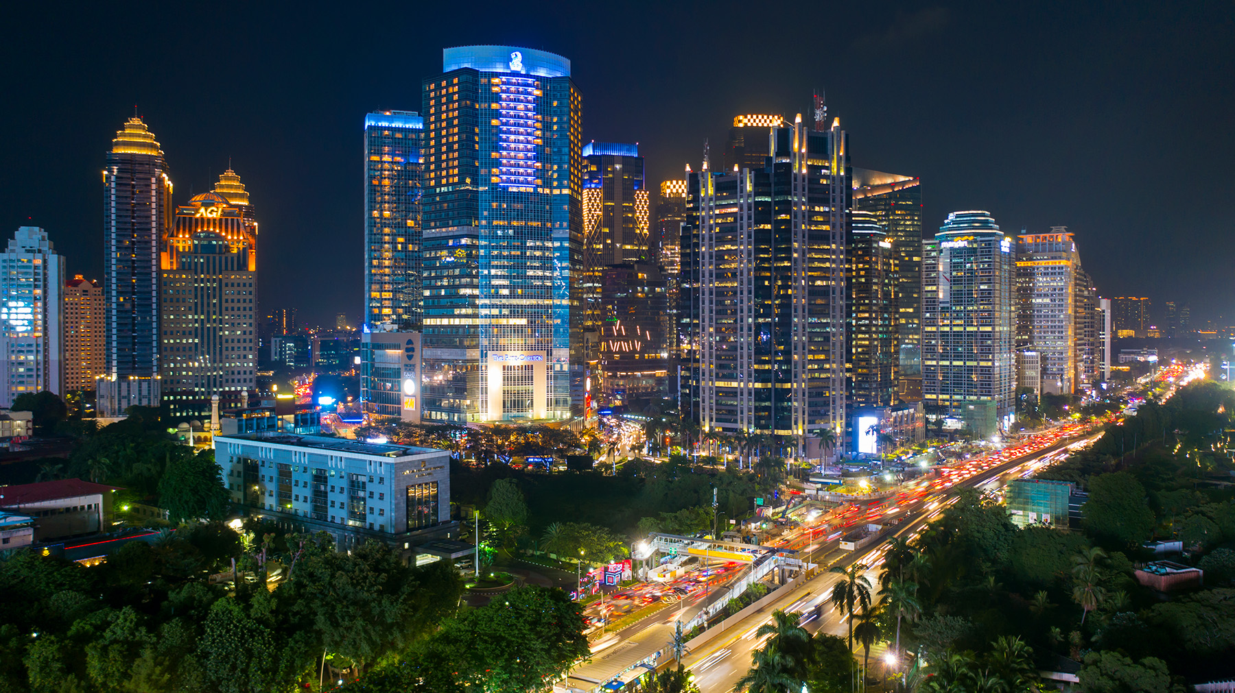 Traffic jam and brightly lit skyscrapers at night.