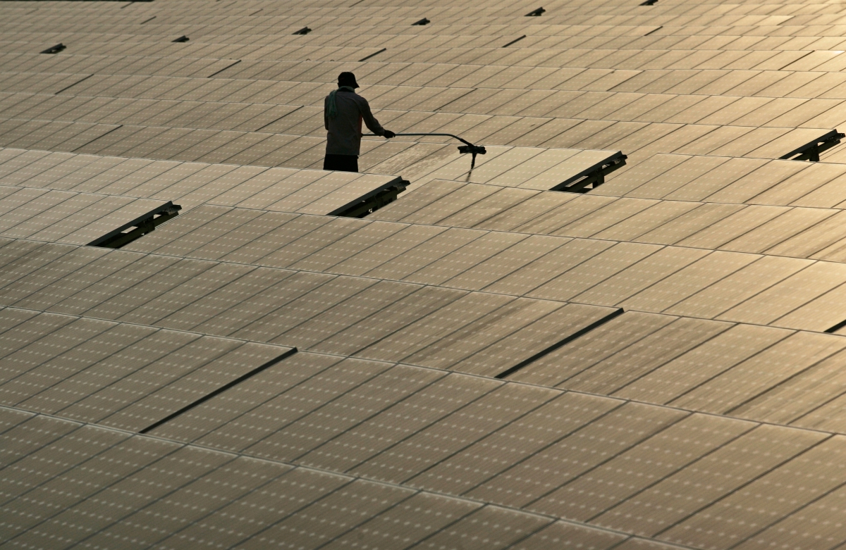 Man cleaning top of solar panels in India