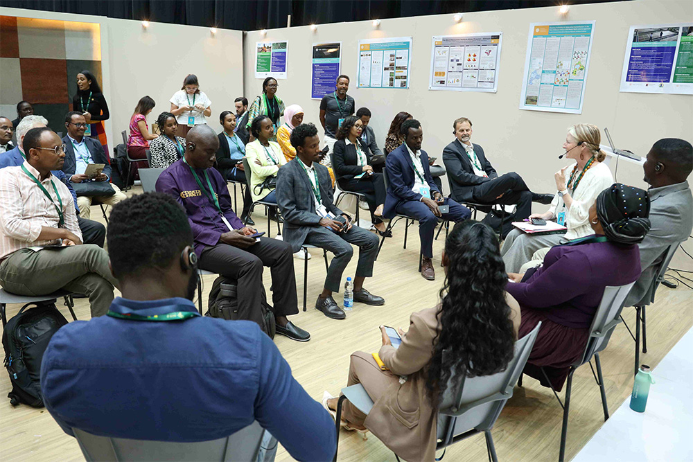 A large group of people sits in a circle for a workshop.