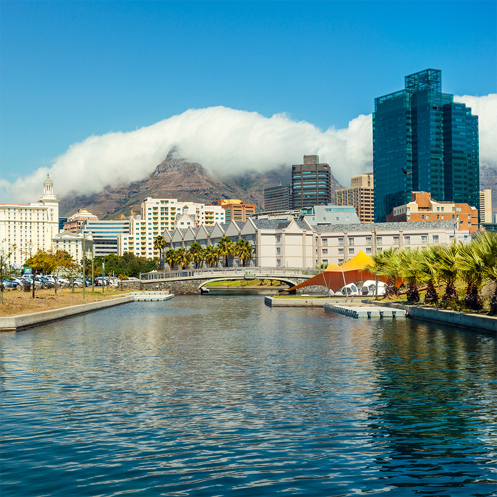 Canal in the forefront looking towards cityscape with mountain in the background.