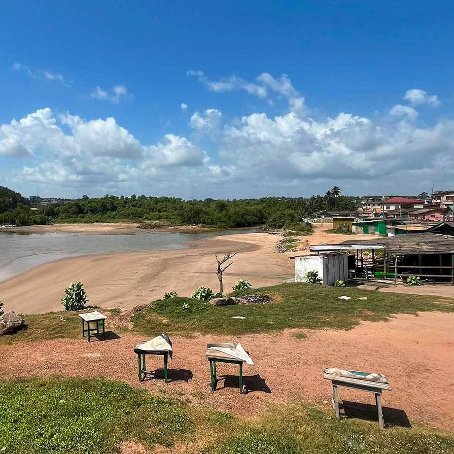 Rustic community on the mouth of a low river with trees on the other bank.