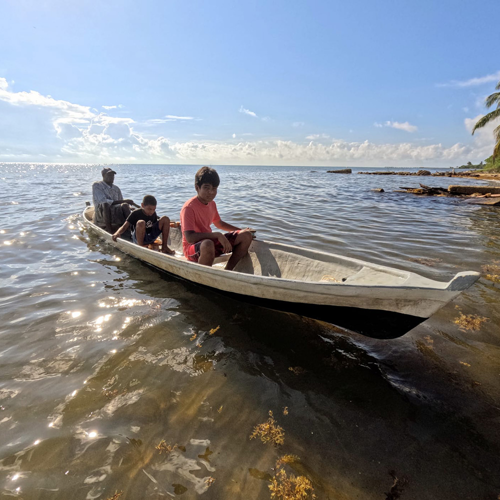 Grandfather sits at the back of a small boat with his two grandchildren in the middle and front.