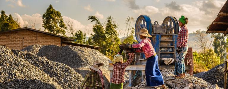 Three women work at an artisanal mine in Asia at dusk
